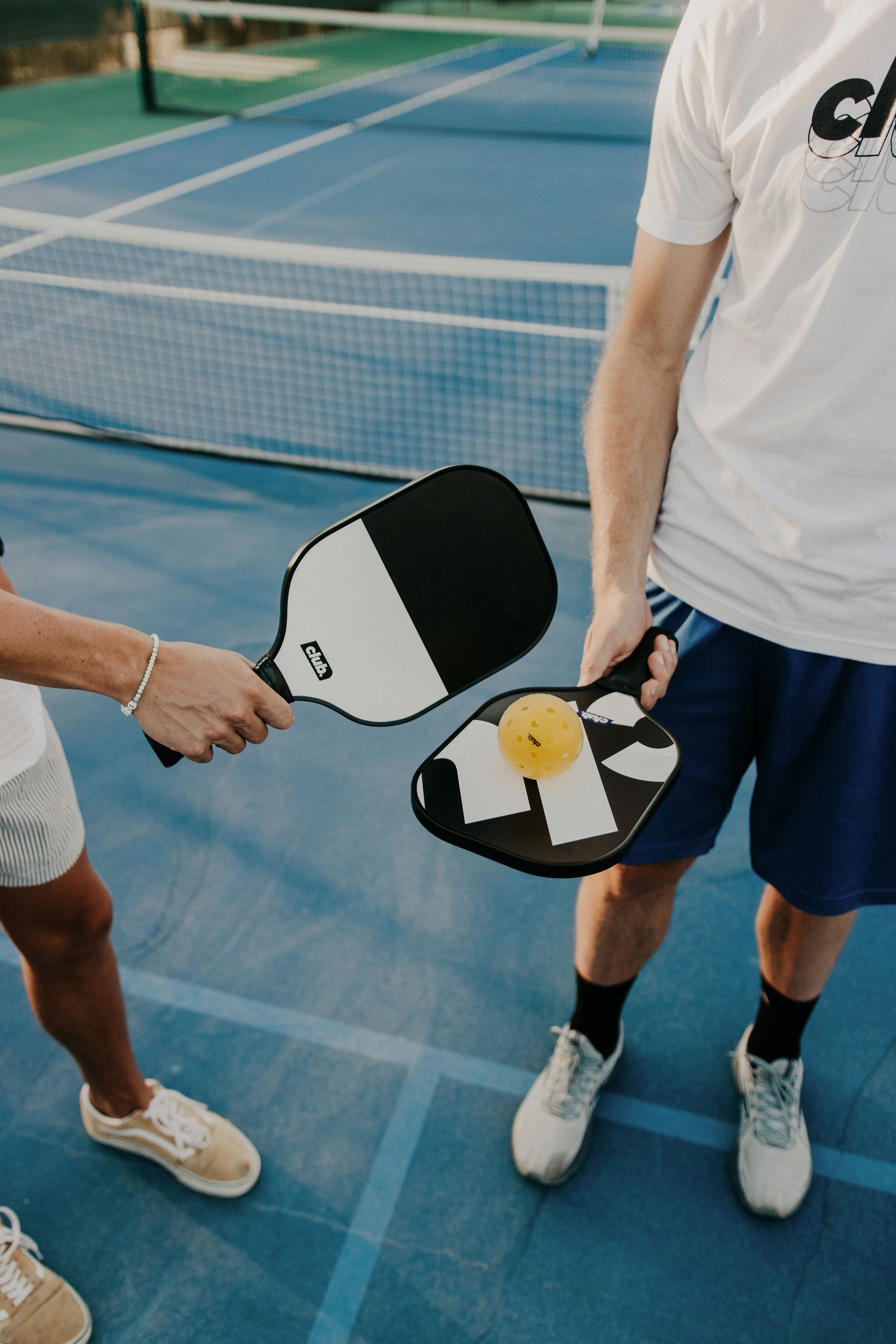 two people use a pickleball paddle set with black and white paddles