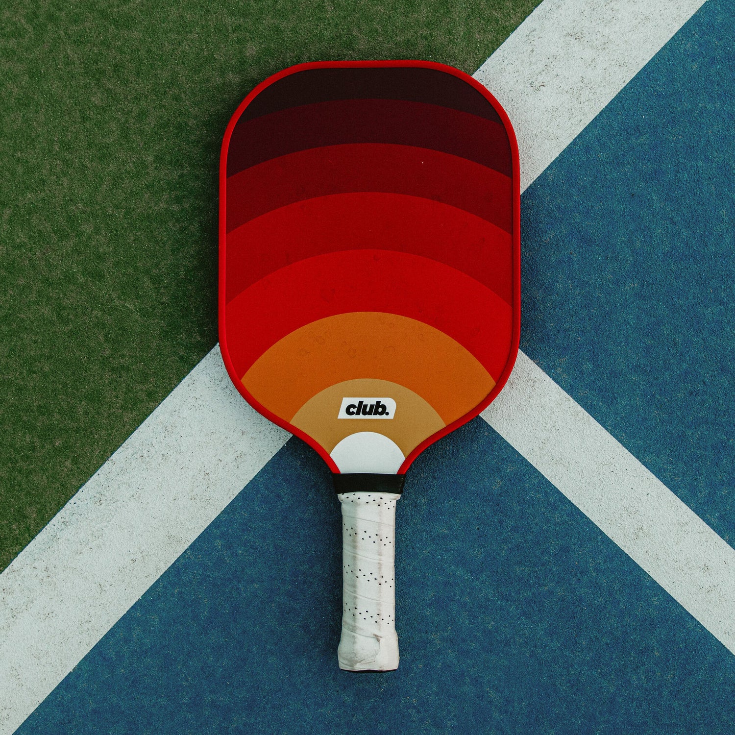 ombre orange and yellow pickleball paddle on a pickleball court for a pickleball starter set